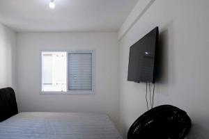 a bedroom with a bed and a flat screen tv at Apto com lazer completo a 500m da Praia da Enseada in Bertioga