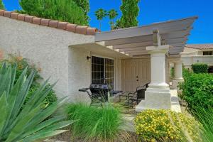 eine Veranda eines Hauses mit zwei Stühlen unter einer Pergola in der Unterkunft Mesquite Desert Bungalow in Palm Springs