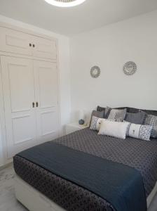 Un dormitorio blanco con una cama grande con almohadas. en Apartamento El Castillo, en Fuengirola