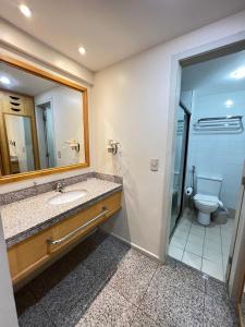 a bathroom with a sink and a toilet and a mirror at Flat Particular em Blue Tree Towers Beira Mar Fortaleza in Fortaleza