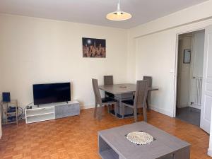a living room with a table and a television at ORLEANS GARE - Résidence calme - T2 - L'ESCALE DE LA GARE in Orléans