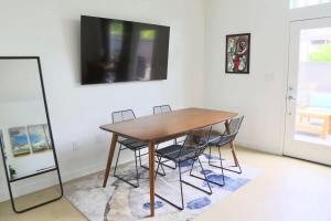 オースティンにあるUpscale 2BR Condo w Patio City Views Walk to DTのダイニングルームテーブル(椅子付)、壁掛けテレビが備わります。