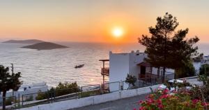 a sunset over the ocean with a white building at Villa in Yalıkavak, Panoramic Sea View and Beach in Bodrum City