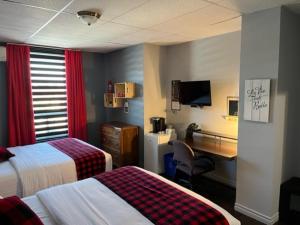 a hotel room with two beds and a desk at Pavillon Beauséjour in Amqui