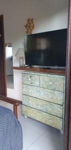 a dresser with a television on top of it at Pé na areia! Canto do Moreira -30 Metros da Praia in São Sebastião