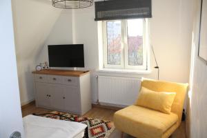 a living room with a yellow chair and a television at AP Apartment's Rodzinny in Wałbrzych