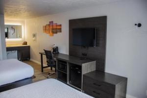 a hotel room with a bed and a desk with a television at Bears Ears Inn in Blanding