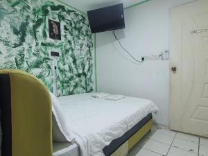 Hotel O Green Leaf Guest Lodge Kk في كوتا كينابالو: غرفة مستشفى بسرير وتلفزيون على الحائط +16 صورة