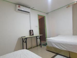 Hotel O Green Leaf Guest Lodge Kk في كوتا كينابالو: غرفة بسرير وطاولة في غرفة