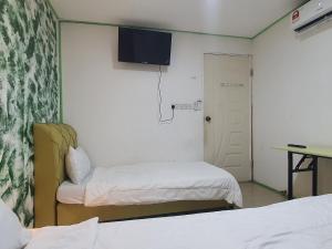 Hotel O Green Leaf Guest Lodge Kk في كوتا كينابالو: غرفة صغيرة بسريرين وباب