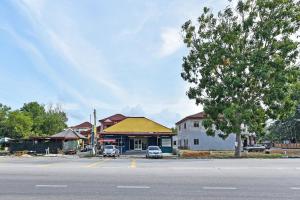 a building on the side of a street with a tree at Hotel O Zn Mix Homestay & Roomstay in Kampung Raja