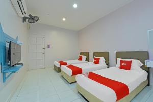 a room with two beds and a tv in it at Hotel O Purple Town in Sekinchan
