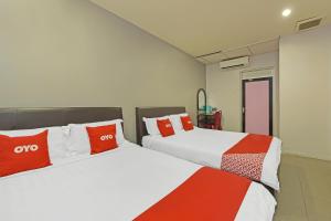 two beds in a hotel room with red pillows at Hotel O Purple Town in Sekinchan