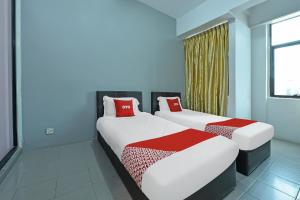 two beds with red pillows in a room at Hotel O Purple Town in Sekinchan