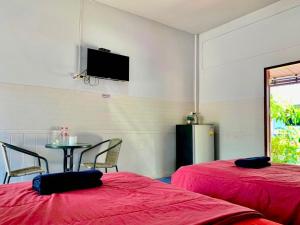 a room with two beds and a table and a tv at Baan Kenpoo Resort in Phetchaburi