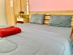 a bed with a red pillow on top of it at Baan Kenpoo Resort in Phetchaburi