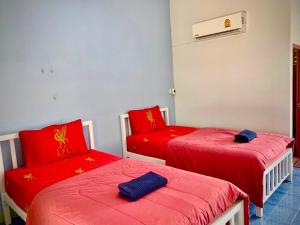 a room with two red beds and a chair at Baan Kenpoo Resort in Phetchaburi +35 photos