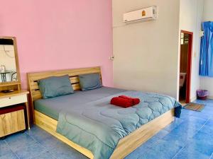 a bedroom with a bed with a red pillow on it at Baan Kenpoo Resort in Phetchaburi