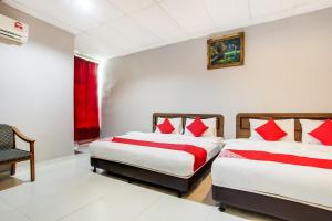 a bedroom with two beds with red pillows at Super OYO 89427 Kavanas Hotel Taiping in Taiping +45 photos