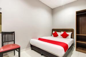 a bedroom with a bed with red pillows and a chair at Super OYO 89427 Kavanas Hotel Taiping in Taiping