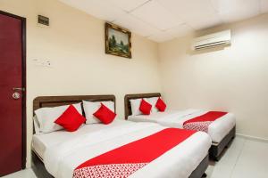 two beds in a hotel room with red pillows at Super OYO 89427 Kavanas Hotel Taiping in Taiping