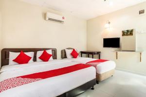 a bedroom with two beds with red pillows and a tv at Super OYO 89427 Kavanas Hotel Taiping in Taiping