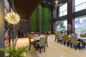 a restaurant with tables and chairs and green walls at Capital O 1200 Salem Riverside Hotel in Da Nang