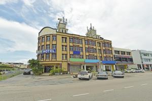a yellow building with cars parked in a parking lot at Hotel O Sam Huat Hotel in Kampong Atap