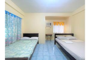 a bedroom with two beds and a table at OYO 876 Escurel Inn Boracay in Boracay