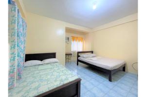 a bedroom with two beds and a table in it at OYO 876 Escurel Inn Boracay in Boracay