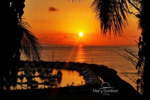 a sunset over the ocean with boats in a marina at Mar y Sombra Villas in Quepos