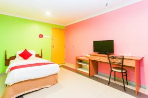 a bedroom with a bed and a desk with a television at Hotel O Comfort in Ipoh