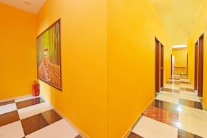 a hallway with yellow walls and a painting on the wall at Hotel O Bamboo Inn in Batu Ferringhi +24 photos