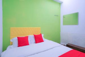 a bedroom with a bed with red and white pillows at Hotel O V Stay Guesthouse in Ayer Itam