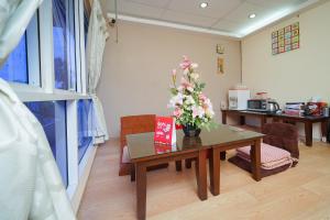 a room with a table with a vase of flowers on it at Hotel O V Stay Guesthouse in Ayer Itam