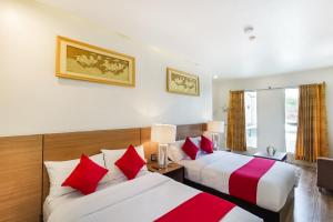 two beds in a hotel room with red and white pillows at OYO 489 Casa Mia Hotel Suites in General Santos