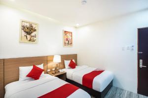 two beds in a hotel room with red and white at OYO 489 Casa Mia Hotel Suites in General Santos