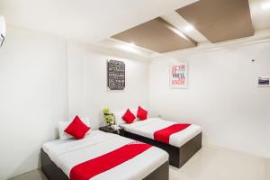 two beds in a room with red and white sheets at OYO 489 Casa Mia Hotel Suites in General Santos