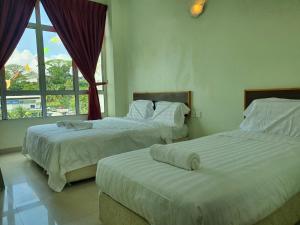 two beds in a room with a window at Hotel O Good View Inn in Sri Aman