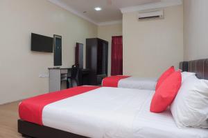 a bedroom with two beds with red pillows and a desk at Hotel O Kay Inn Kerteh in Kertih +33 photos