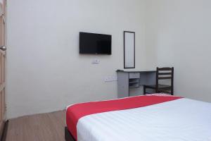 a bedroom with a bed and a desk and a tv at Hotel O Kay Inn Kerteh in Kertih