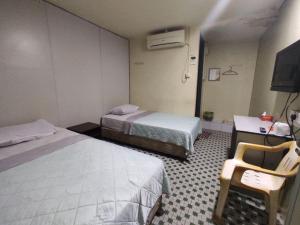 a hotel room with two beds and a desk and a tv at Hotel O 59 in Sibu +18 photos