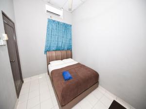 a small bed in a small room with a blue pillow at Hotel O Iman Roomstay Gua Musang in Gua Musang
