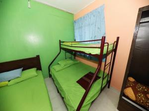 two bunk beds in a room with green walls at Hotel O Bayu Chalet in Kota Bharu