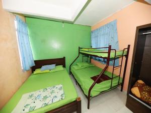 two bunk beds in a room with green walls at Hotel O Bayu Chalet in Kota Bharu