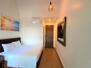 a bedroom with a white bed and a tv at Capital O 1194 Bee Hotel in Xóm Cầu Hin +30 photos