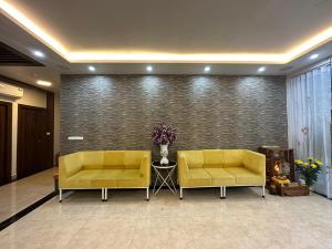 two yellow couches in a lobby with a wall at Capital O 1194 Bee Hotel in Xóm Cầu Hin