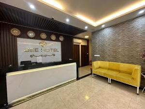 a lobby of a hotel with a yellow bench and a sign at Capital O 1194 Bee Hotel in Xóm Cầu Hin