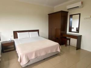 a bedroom with a bed and a dresser and a mirror at Gold Hill Hotel Jerantut in Jerantut