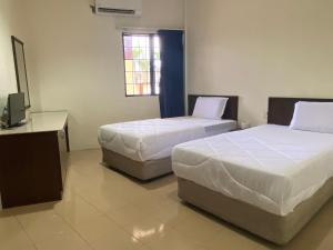 a bedroom with two beds and a television in it at Gold Hill Hotel Jerantut in Jerantut